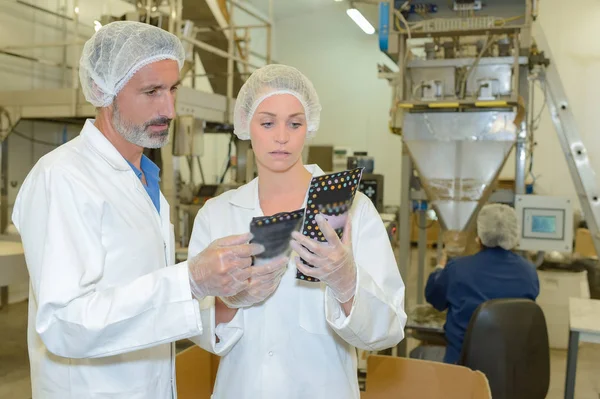 Homme et femme examinant des paquets dans l'usine — Photo