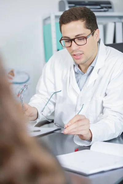 Ung skicklig ögonläkare pratar med kvinnlig patient — Stockfoto