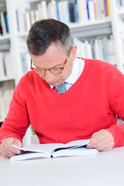 Un hombre inteligente leyendo en una biblioteca —  Fotos de Stock