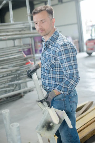 Ouvrier tenant un poteau métallique — Photo