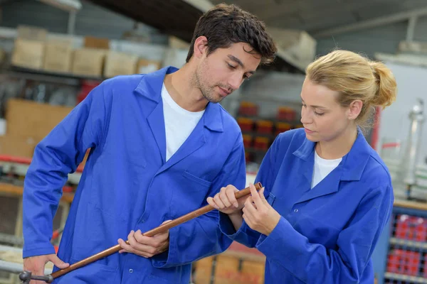 Dois jovens trabalhadores manuais inspecionando tubo de cobre — Fotografia de Stock