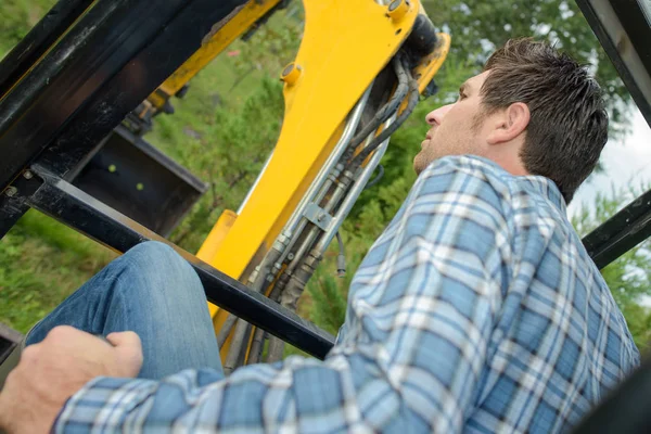 Mann bedient Bagger und Bauarbeiter — Stockfoto