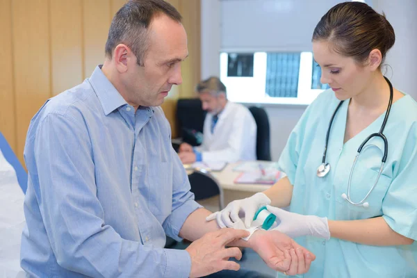 Infirmière appliquant du ruban adhésif sur le poignet du patient — Photo