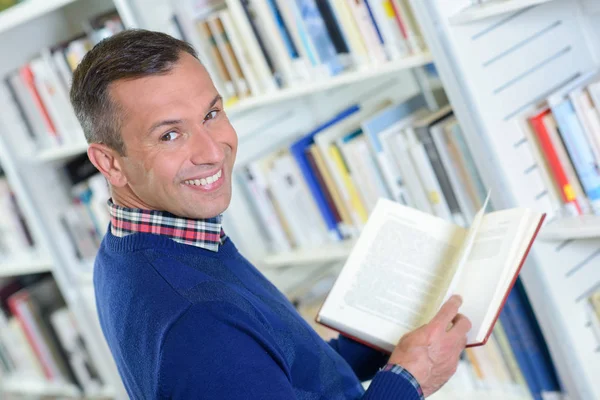 Człowiek w bibliotece, toczenia i uśmiechając się — Zdjęcie stockowe