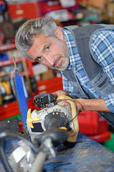 Mechanic with strimmer on workbench — Stock Photo, Image