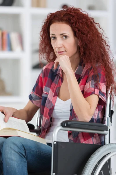 Disabilty and handicap young disabled woman on wheelchair reads book — Stock Photo, Image