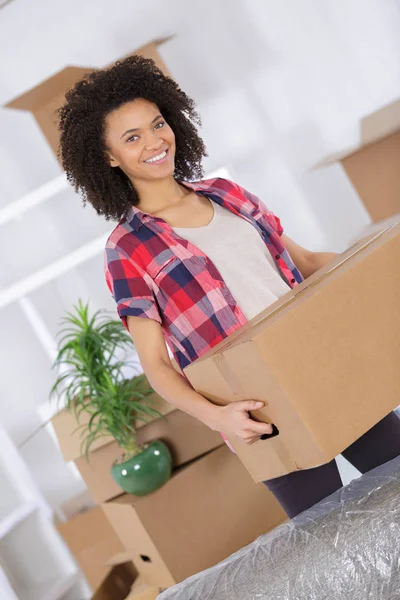 Mujer moviendo casas sonriendo y llevando una caja de cartón — Foto de Stock