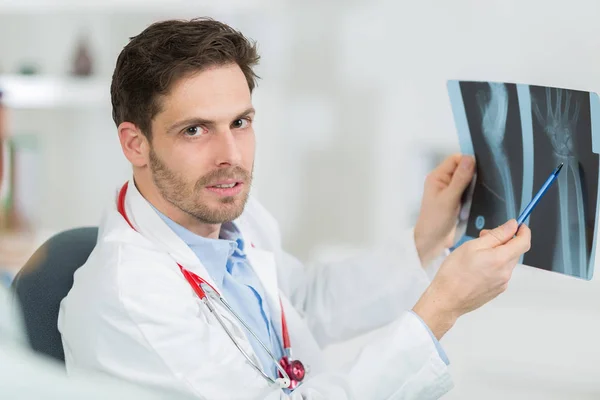 Arzt am Schreibtisch hält und überprüft Trauma-Röntgen — Stockfoto