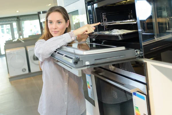 Femme regardant ove dans le magasin d'appareils ménagers — Photo