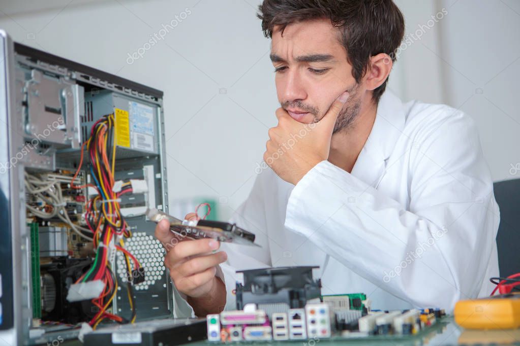 Confused computer technician studying component \u2014 Stock Photo \u00a9 photography33 #136838692
