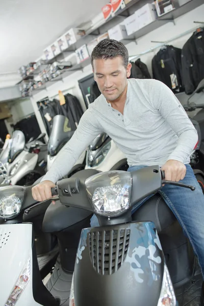 Mannen satt på moderna scooter i showroom — Stockfoto
