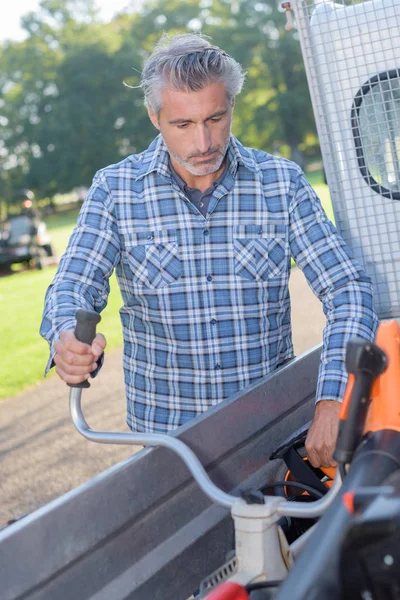 Uomo carico strimmer nel veicolo di lavoro — Foto Stock