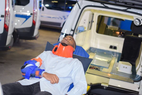 Braccialetto uomo al collo accanto all'ambulanza — Foto Stock