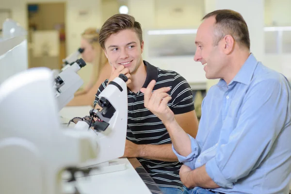 Dos hombres charlando junto a un microscopio — Foto de Stock