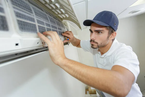 Portret van halverwege volwassen mannelijke technicus reparatie Air Conditioner — Stockfoto