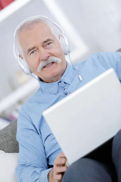 Senior con un computer portatile su un divano — Foto Stock