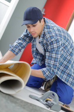 close up of male worker unrolling carpet in office clipart