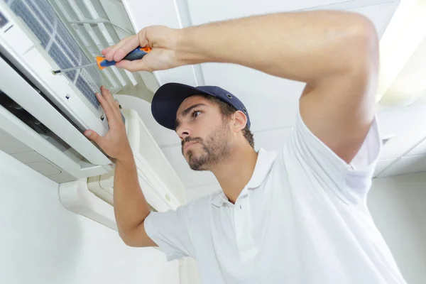 Portret van halverwege volwassen mannelijke technicus reparatie Air Conditioner — Stockfoto