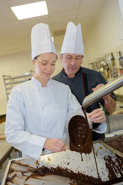 Cheerful young woman professional pastry uses chocolate for tasty recipe — Stock Photo, Image