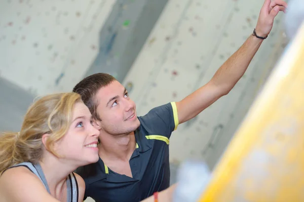 Jovem casal apontando para cima na parede de escalada — Fotografia de Stock