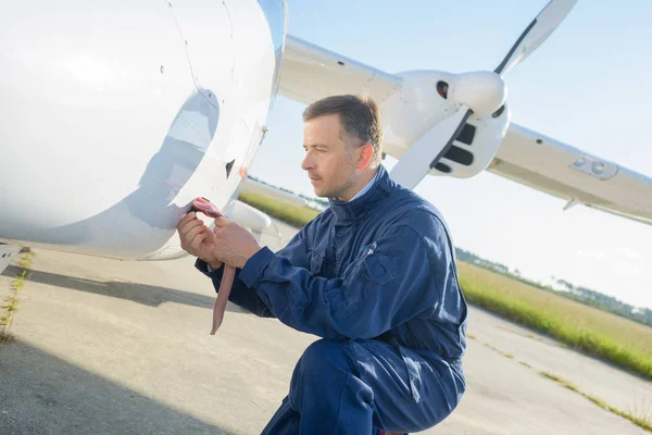 Mechanic kneeling beside aircraft — Stock Photo, Image
