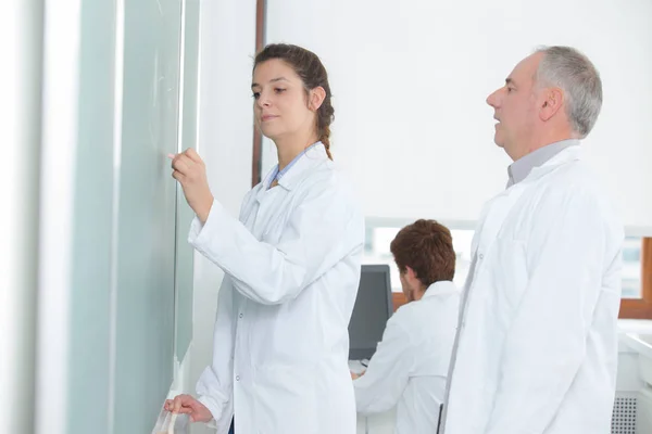 Enseignant regardant l'élève écrire sur le tableau blanc — Photo