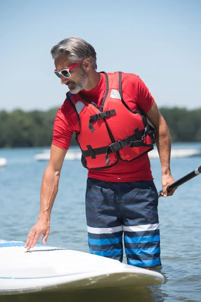 Uomo accanto a un trampolino stand-up sul lago — Foto Stock