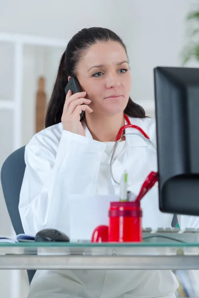 Beautiful young female doctor sitting at the desk — Stock Photo, Image