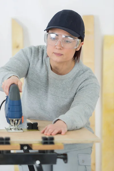 Жінка використовує стрічковий наконечник для вирізання шматка дерева — стокове фото