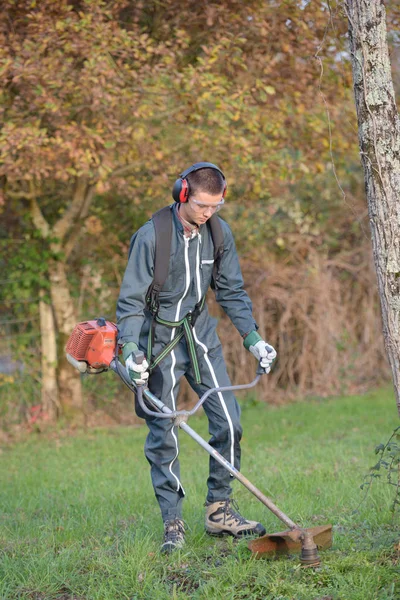 Giovane uomo strimming e strimmer — Foto Stock