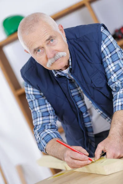 Senior timmerman markering woodboard in werkplaats — Stockfoto