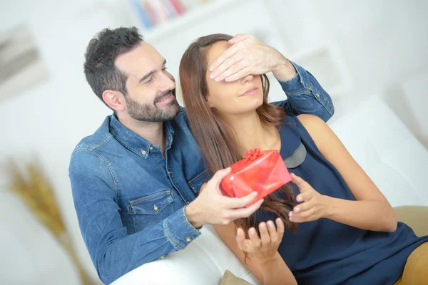 Young attentive man offering gift to his beloved girlfriend — Stock Photo, Image