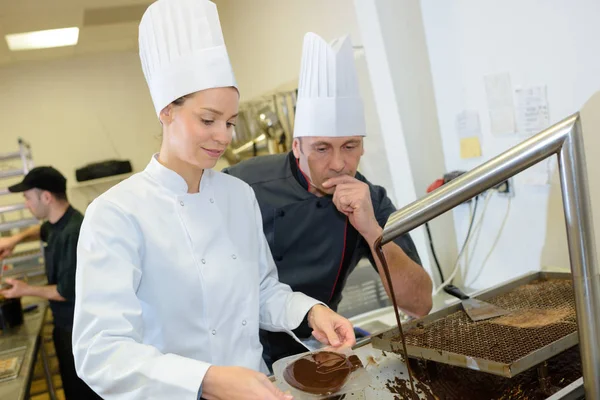 शेफ आणि सहाय्यक पेस्ट्रीसाठी चॉकलेट भरा तयार करतात — स्टॉक फोटो, इमेज
