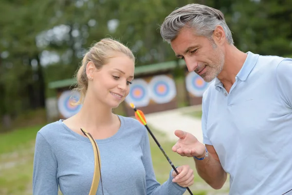 Hombre y mujer mirando flechas de tiro con arco — Foto de Stock