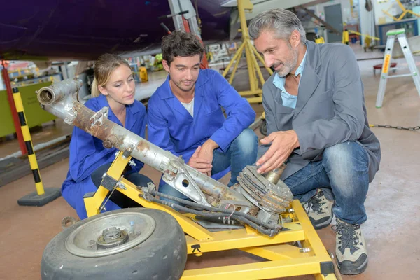 Tecnici che guardano al carrello di atterraggio dell'aeromobile smantellato — Foto Stock