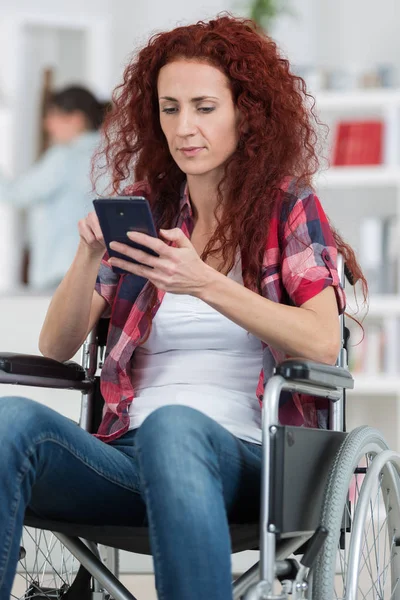 Handicapped redhead woman texting and surfing on her smartphone — Stock Photo, Image