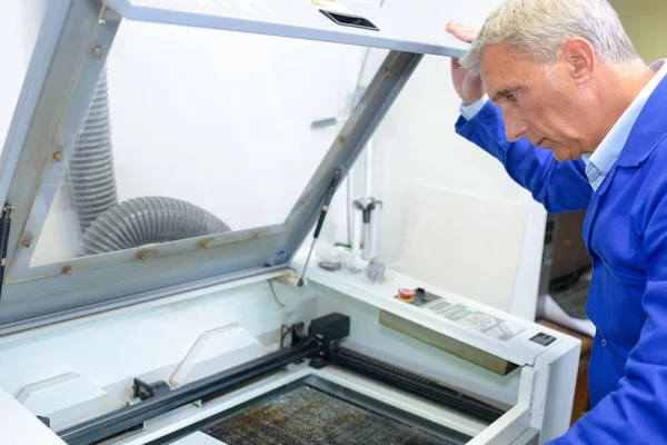 Mature man looking into printing machine — Stock Photo, Image