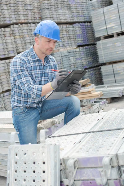 Arbeiter im Bauhof schreibt auf Klemmbrett — Stockfoto