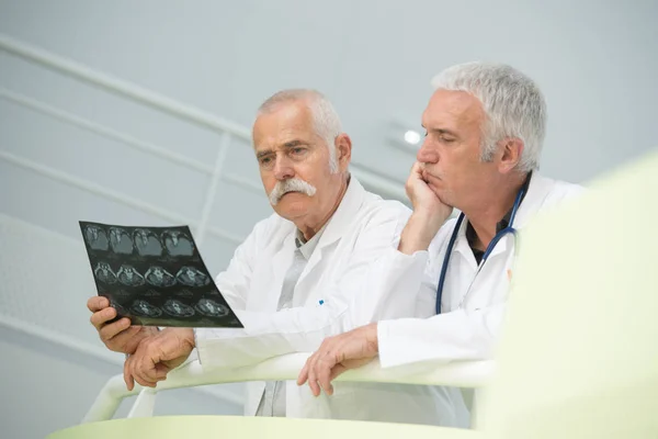 Médicos mayores mirando perplejos sobre rayos X — Foto de Stock