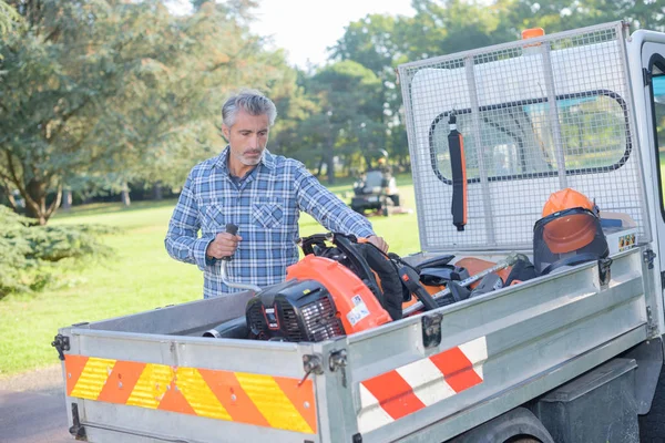 Homem que carrega o equipamento de jardinagem no veículo — Fotografia de Stock