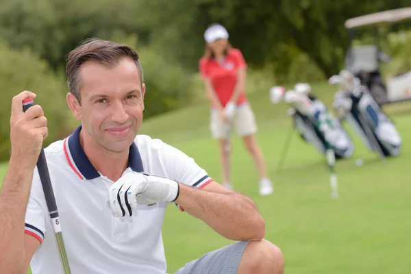 Porträt eines männlichen Golfers, Ehefrau spielt im Hintergrund — Stockfoto