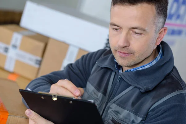 Deponun içinde clipboard ile mutlu teslimatçı — Stok fotoğraf