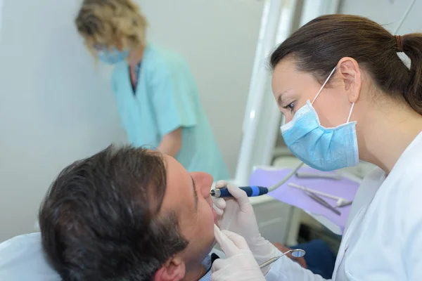 Οδοντίατρος χρησιμοποιώντας εφαρμογή στα δόντια του ασθενούς — Φωτογραφία Αρχείου