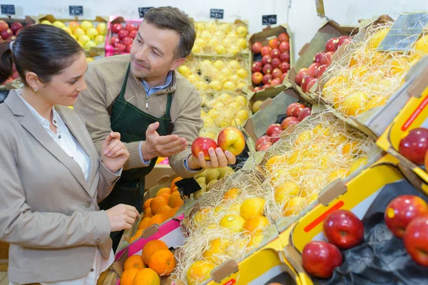 微笑的女人选择不同的水果在农场食品商店显示 — 图库照片