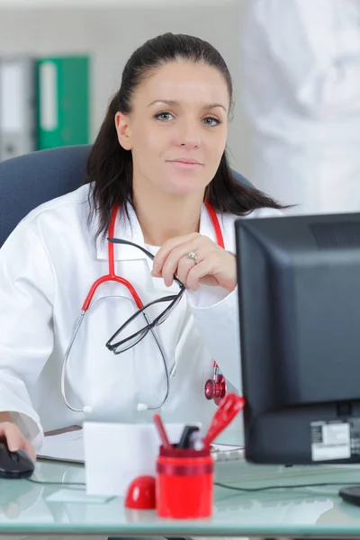 Προσωπογραφία νεαρής γυναίκας γιατρού που κάθεται στο γραφείο στο νοσοκομείο — Φωτογραφία Αρχείου