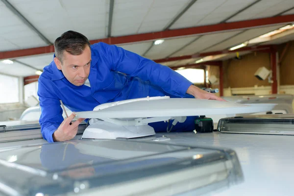 Mechanic fitting satellite receiver to roof of camper van — Stock Photo, Image