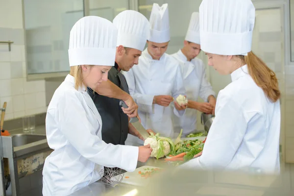 Team angehender Köche bereitet Gemüse zu — Stockfoto