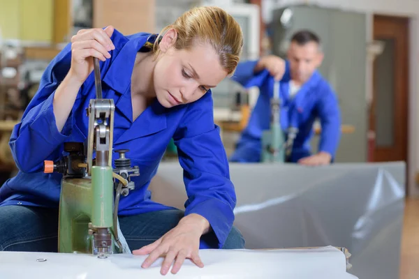 Kvinnan använder machine för att stansa hål i materialet — Stockfoto