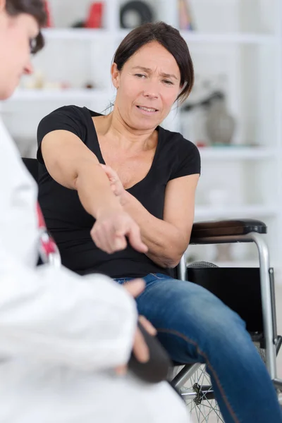 Behinderte Frau klagt während Sprechstunde über Armschmerzen — Stockfoto