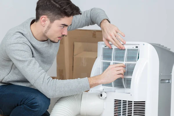 Apuesto joven electricista instalación de aire acondicionado en la casa del cliente —  Fotos de Stock